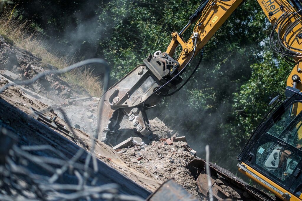 achinaal sloopwerk uitgevoerd door Aannemingsbedrijf Henk Verhoef, waarbij een sloopkraan een constructie gecontroleerd afbreekt.